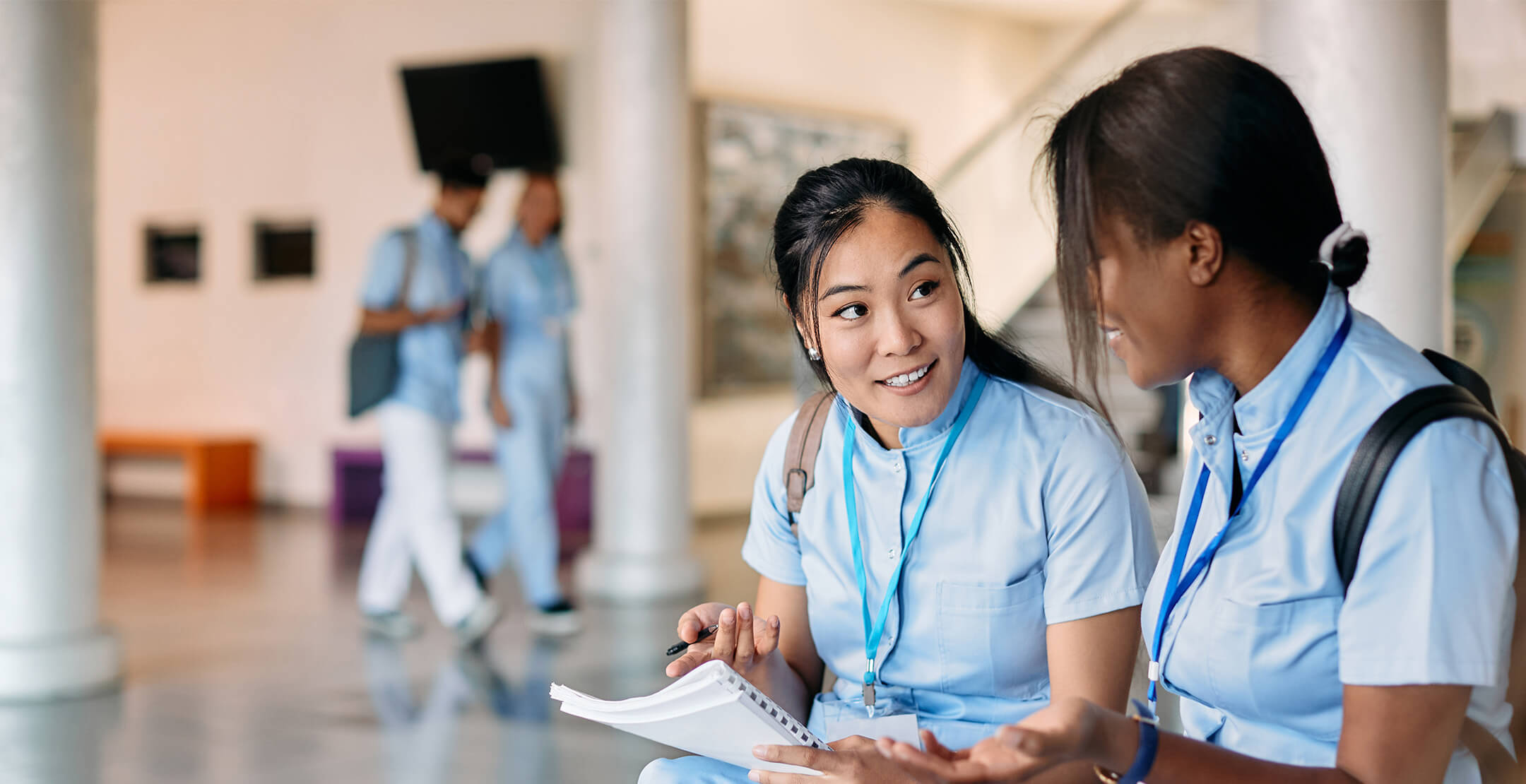 Two female physicians sitting side by side and discussing notes