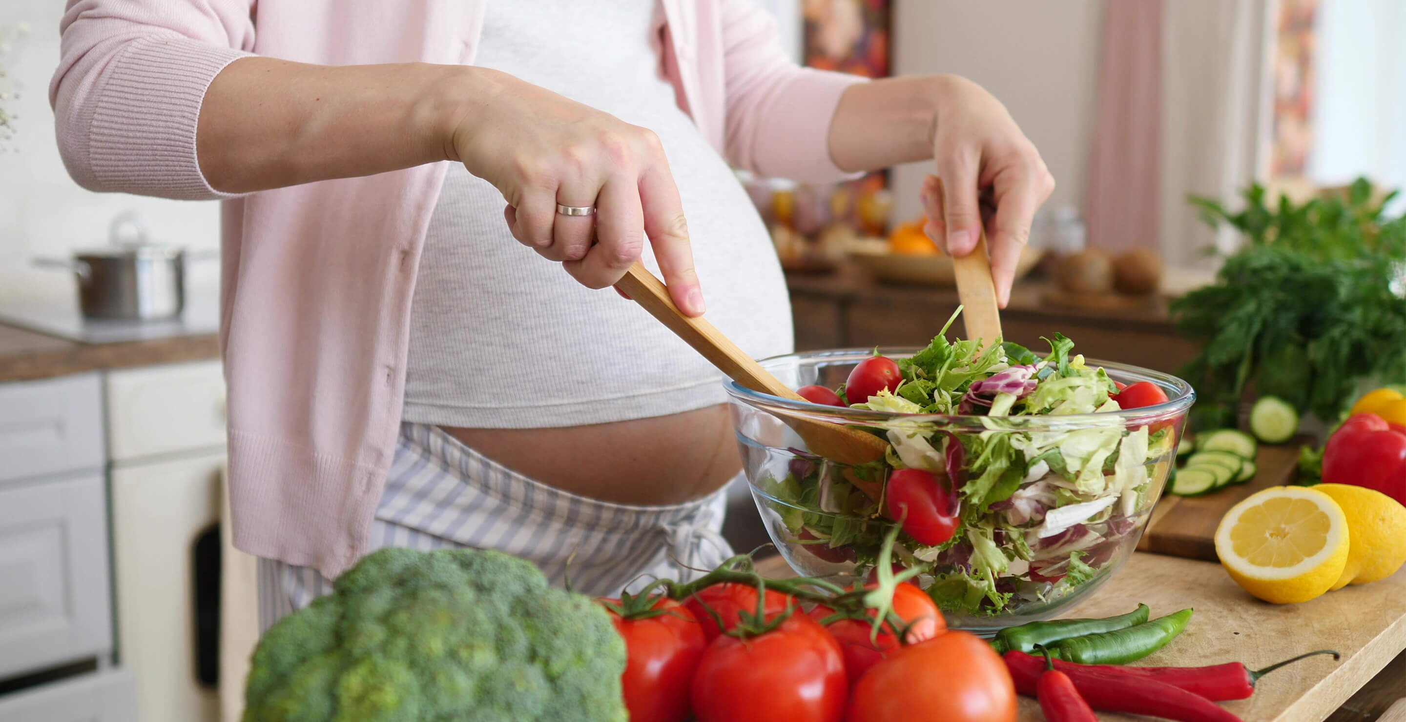 Image of a pregnant woman as she prepares a green salad